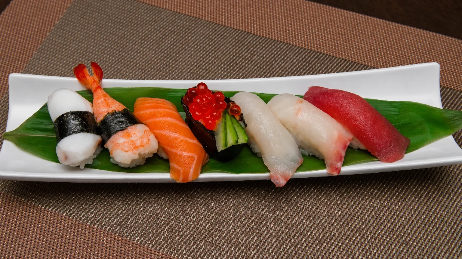 Illustration: Sushi on a white plate, on a brown placemat.