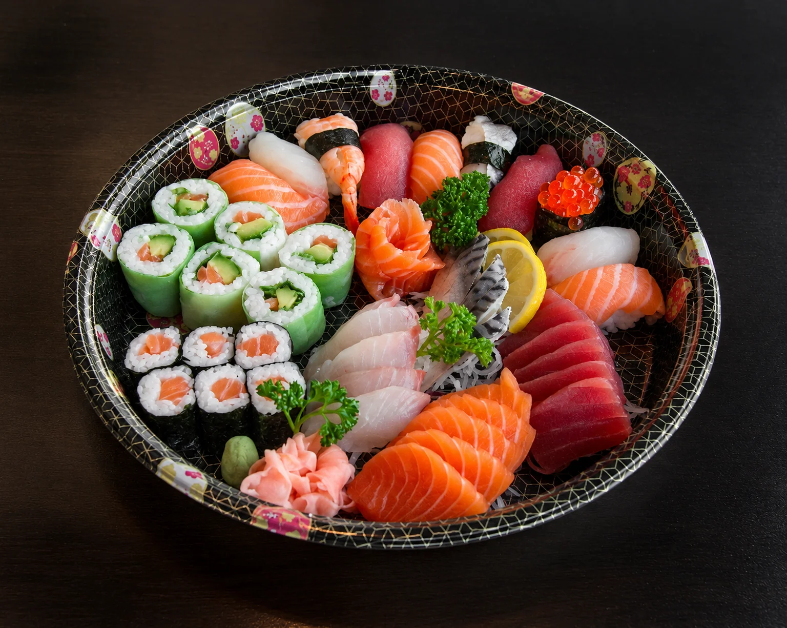 Illustration: Sushi and sashimi on a round black platter.