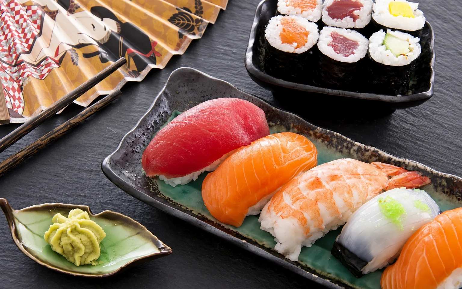 Illustration: Sushi and maki on black plates.